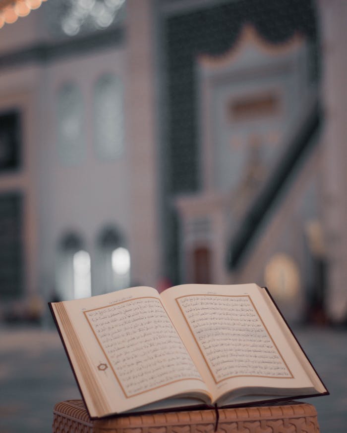 High angle of opened Koran book placed on stone stand in yard of ancient mosque